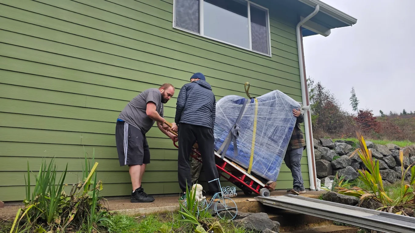 Three movers walking a wrapped hot tub down a walk ramp